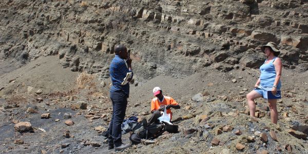 On the left side (Nelson Nhamutole-PhD student), and his main supervisor Prof. Marion Bamford (on the right side) discussing some important aspects regarding the outcrop sampling in the Michunwa outcrop. On the middle (Imede Macungo), a local guide from Tulo locality  packing some collected samples.